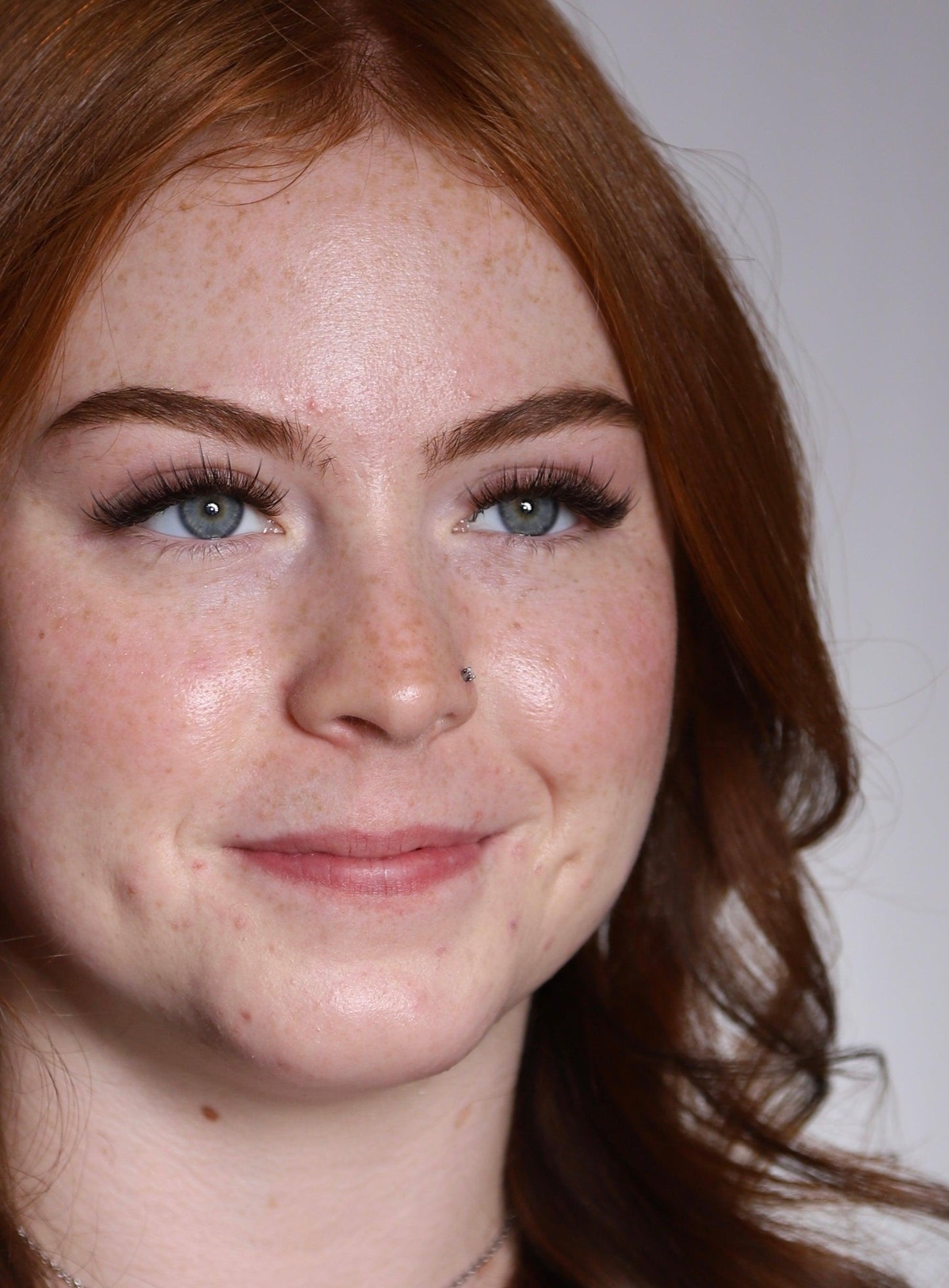 Young woman with red hair, freckles, and Russian mega volume eyelash extensions.